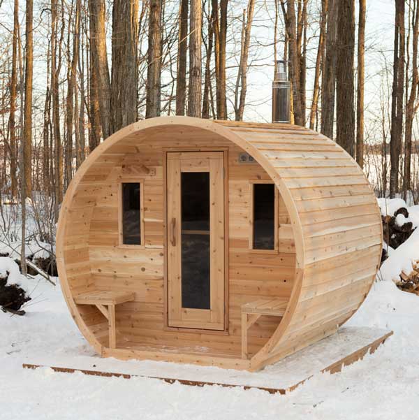 Wooden barrel-shaped sauna in a snowy forest setting